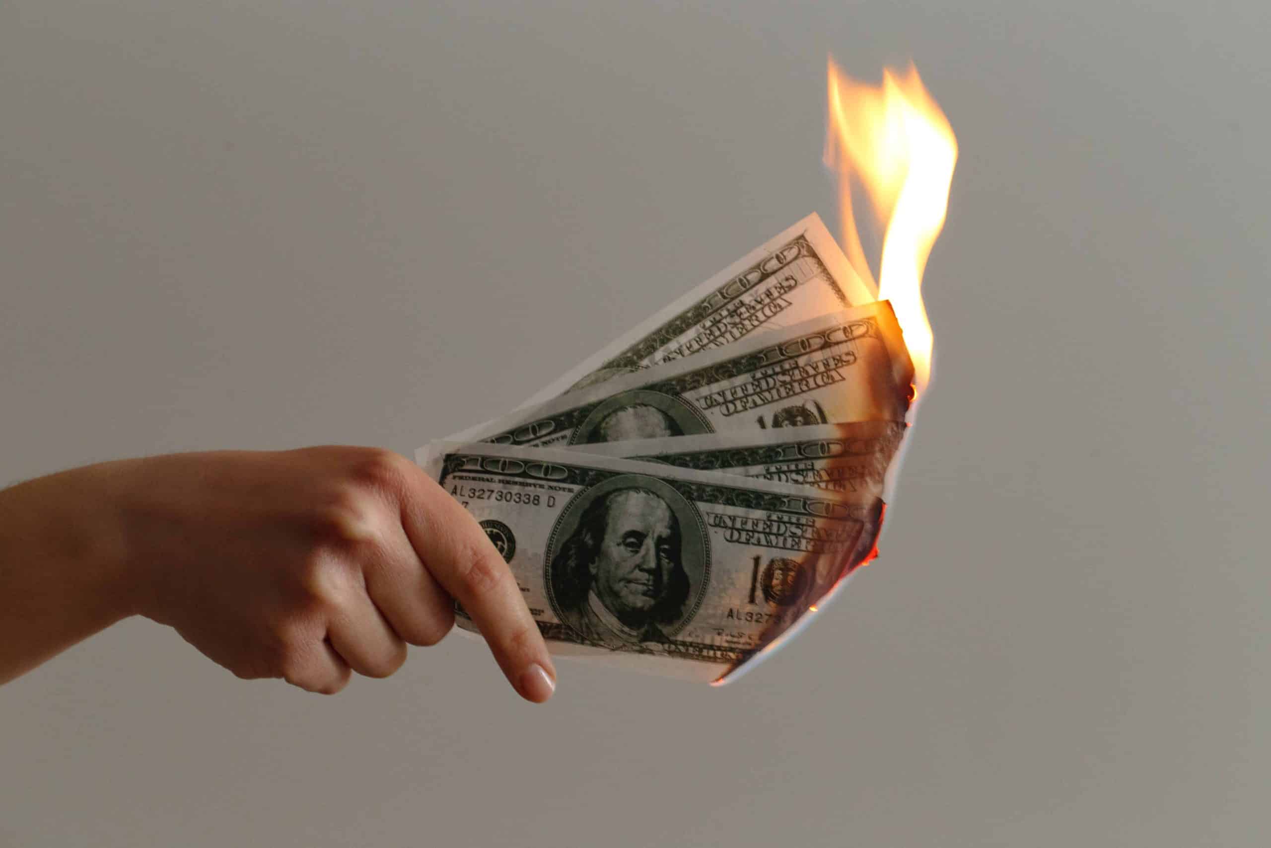 Hand holding burning US dollars